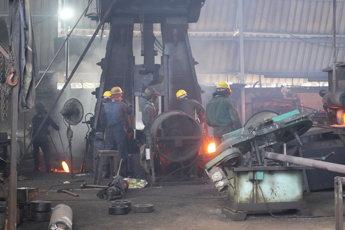 Forging shop with a hot workpiece glowing under the hammer