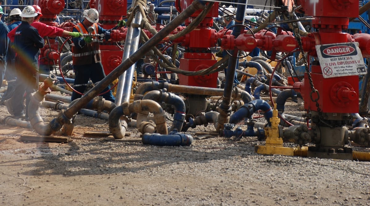 Flowline iron at hydraulic fracturing wellheads, with red valves, hammer union connections and long-radius loops